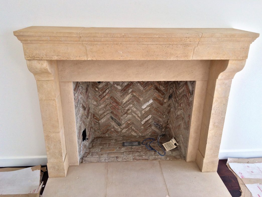 Cast stone fireplace mantel with herringbone brick firebox